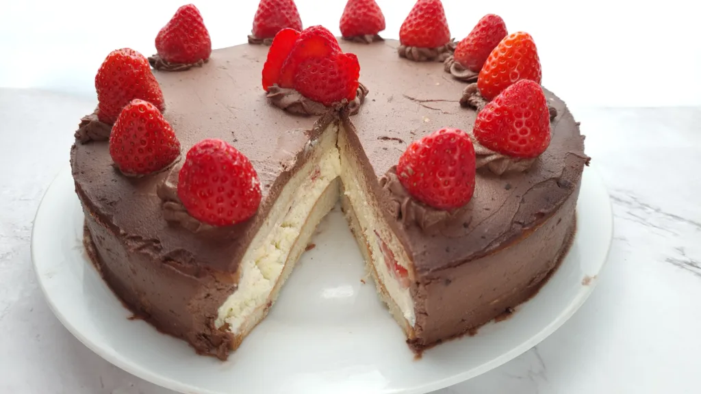 A delicious keto chocolate cake adorned with fresh strawberries and cream, a slice revealing the moist layers within.