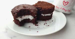 A delicious Keto Oreo Mug Cake with a rich, chocolatey flavor and creamy filling, served on a white plate beside a mug with ‘Have A Mug Cake’ written on it.