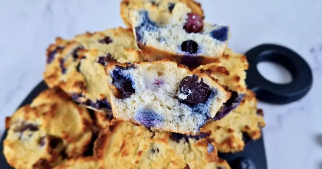 A close-up view of Keto Blueberry Muffins made with coconut flour, showcasing their golden-brown tops and moist, berry-filled interior.