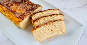 A freshly baked loaf of keto-friendly Cottage Cheese Bread with Almond Flour, showcasing a golden-brown crust and a soft, airy interior, served on a white plate.