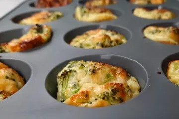 A tray of freshly baked cottage cheese egg muffins with pancetta, showing the golden-brown tops and visible bits of green herbs.