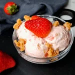 A delectable serving of Keto Strawberry Cottage Cheese Ice Cream, garnished with a fresh strawberry and crumbly topping, presented in an elegant bowl, perfect for a low-carb dessert option.