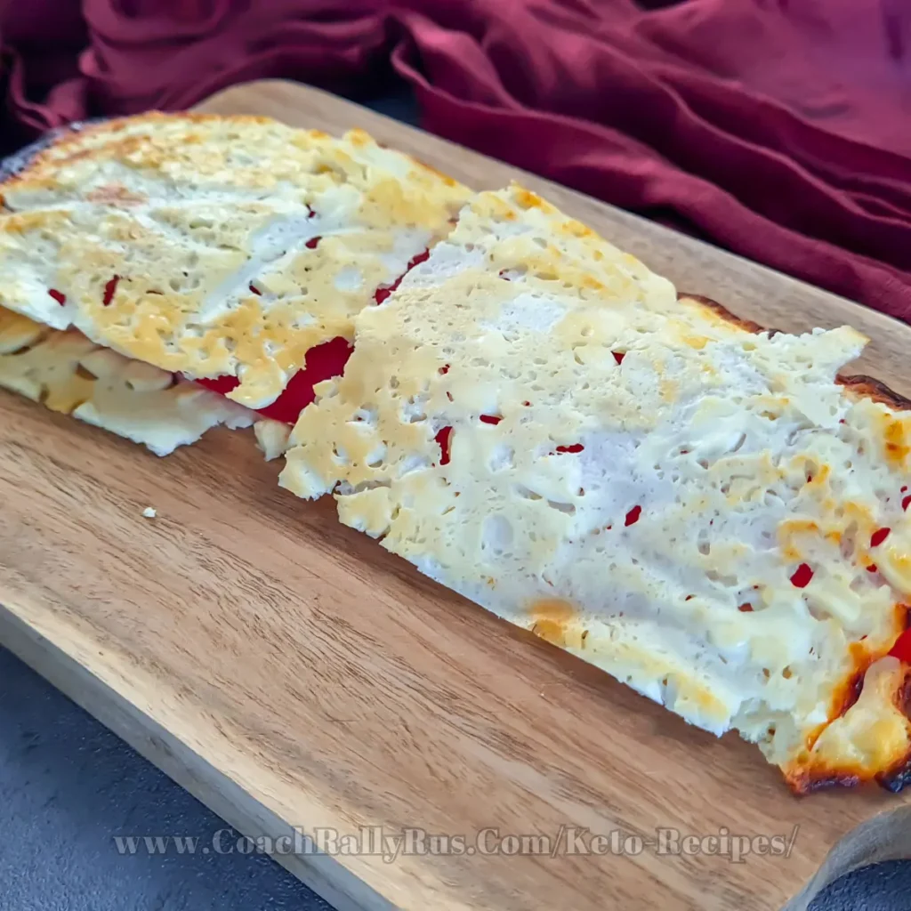 A golden-brown cottage cheese flatbread, freshly baked and full of texture with small, white lumps of cottage cheese visible, sits on parchment paper inside a baking tray, showcasing its homemade, high-protein, and low-carb qualities.