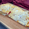 A golden-brown cottage cheese flatbread, freshly baked and full of texture with small, white lumps of cottage cheese visible, sits on parchment paper inside a baking tray, showcasing its homemade, high-protein, and low-carb qualities.