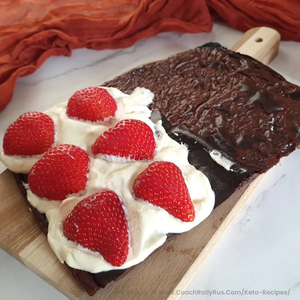 A freshly baked Chocolate Cottage Cheese Flatbread, topped with a creamy layer and adorned with six ripe strawberries, presented on a wooden cutting board with an orange cloth in the background, ready to be enjoyed.