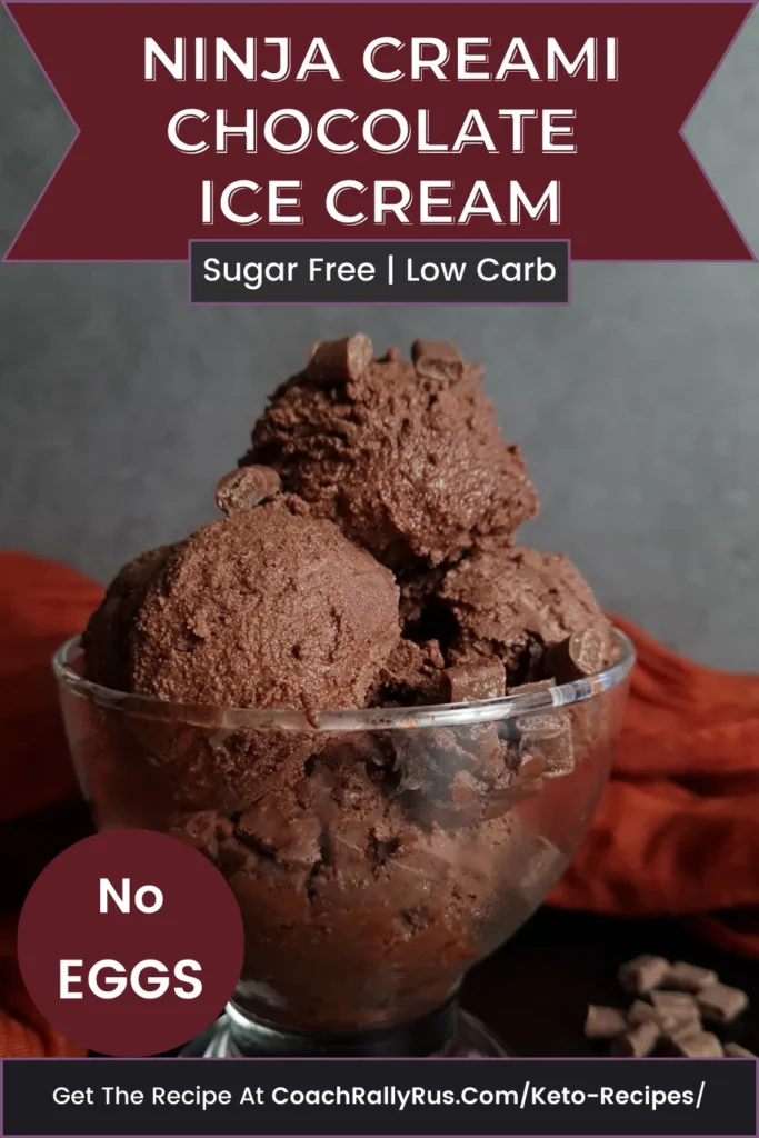 A bowl of Ninja Creami Keto Chocolate Ice Cream, which is sugar-free and low carb, with a label stating ‘No Eggs’. The ice cream is presented in a clear glass bowl against a dark backdrop with an orange cloth underneath. Scattered chocolate pieces are visible around the bowl. The text at the bottom invites viewers to get the recipe at CoachRallyRus.com/Keto-Recipes.