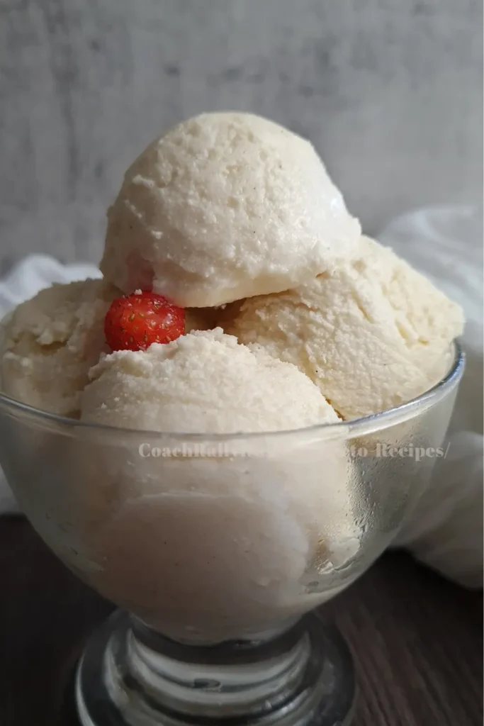 A clear glass bowl filled with scoops of Ninja Creami Keto Vanilla Ice Cream, topped with a small fresh strawberry. The ice cream has a smooth and creamy texture, indicative of the Ninja Creami’s ability to create rich frozen desserts suitable for a ketogenic diet.
