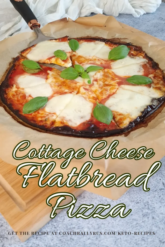 A freshly baked Cottage Cheese Flatbread Pizza Margherita with a golden-brown crust, topped with melted mozzarella cheese, vibrant red tomato sauce, and fresh green basil leaves. The pizza is presented on parchment paper with a pizza cutter alongside. Text overlay states ‘Cottage Cheese Flatbread Pizza’ and prompts to get the recipe at a website link.
