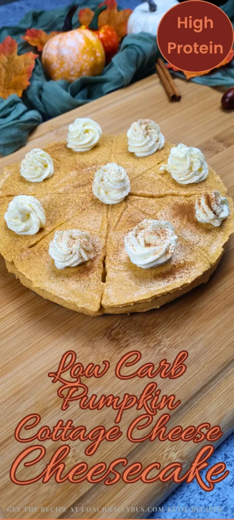 “Low Carb Pumpkin Cottage Cheese Cheesecake topped with whipped cream and a dusting of spice, presented on a wooden board with autumn leaves and mini pumpkins in the background, labeled as ‘High Protein’.