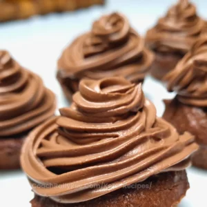 Close-up of a rich, creamy chocolate frosting piped in a swirling pattern atop cupcakes, indicative of a keto-friendly recipe.