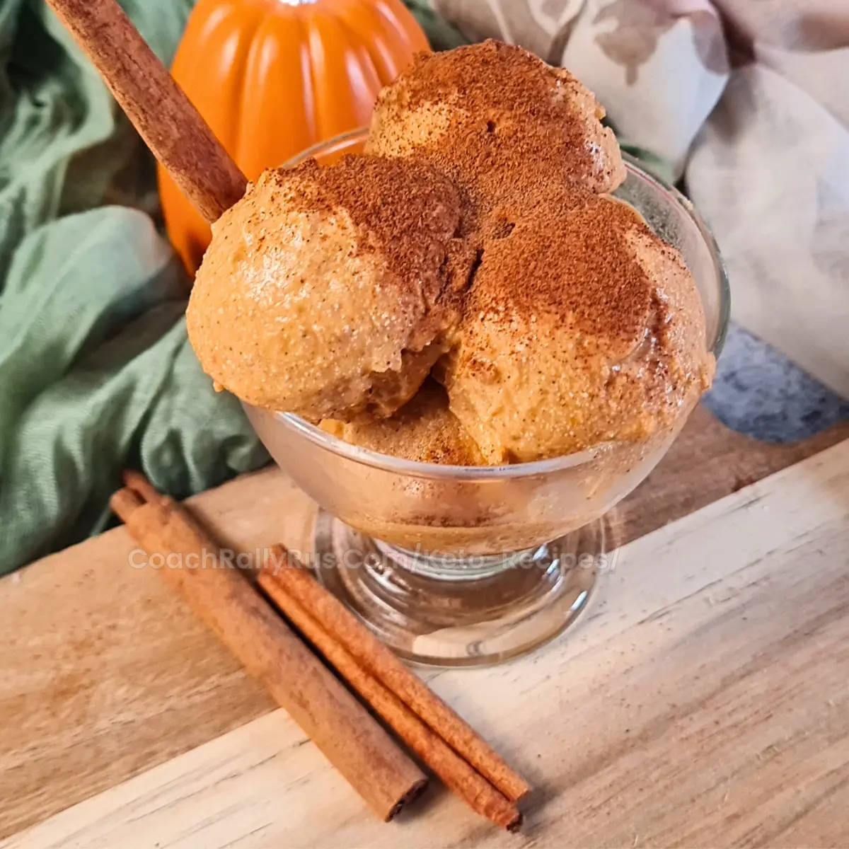 A glass bowl filled with scoops of pumpkin cottage cheese keto ice cream, sprinkled with cinnamon, accompanied by cinnamon