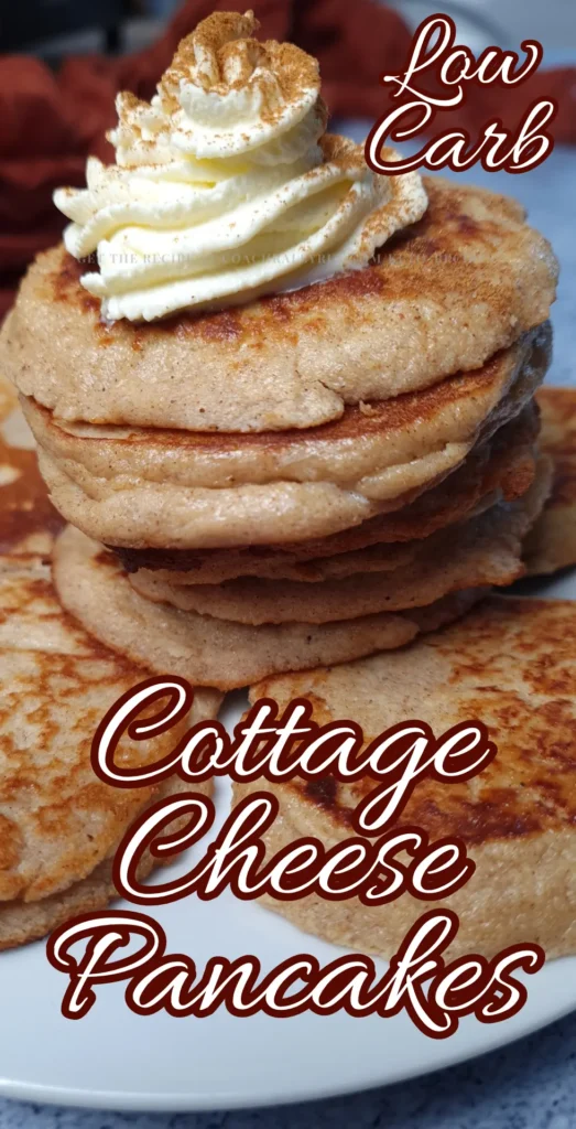A stack of golden-brown Keto Gingerbread Cottage Cheese Pancakes topped with a dollop of whipped cream, served on a white plate.