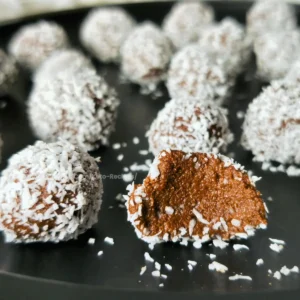 Keto-friendly chocolate rum balls coated with coconut, made with cottage cheese.