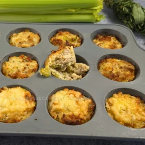 Muffin tin with keto sausage stuffing muffins, one removed to show its interior texture.