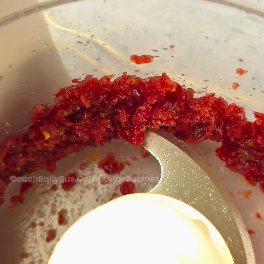 Spiced Keto Cranberry-Orange Relish in a bowl, ready to serve, garnished with orange zest and cranberries.