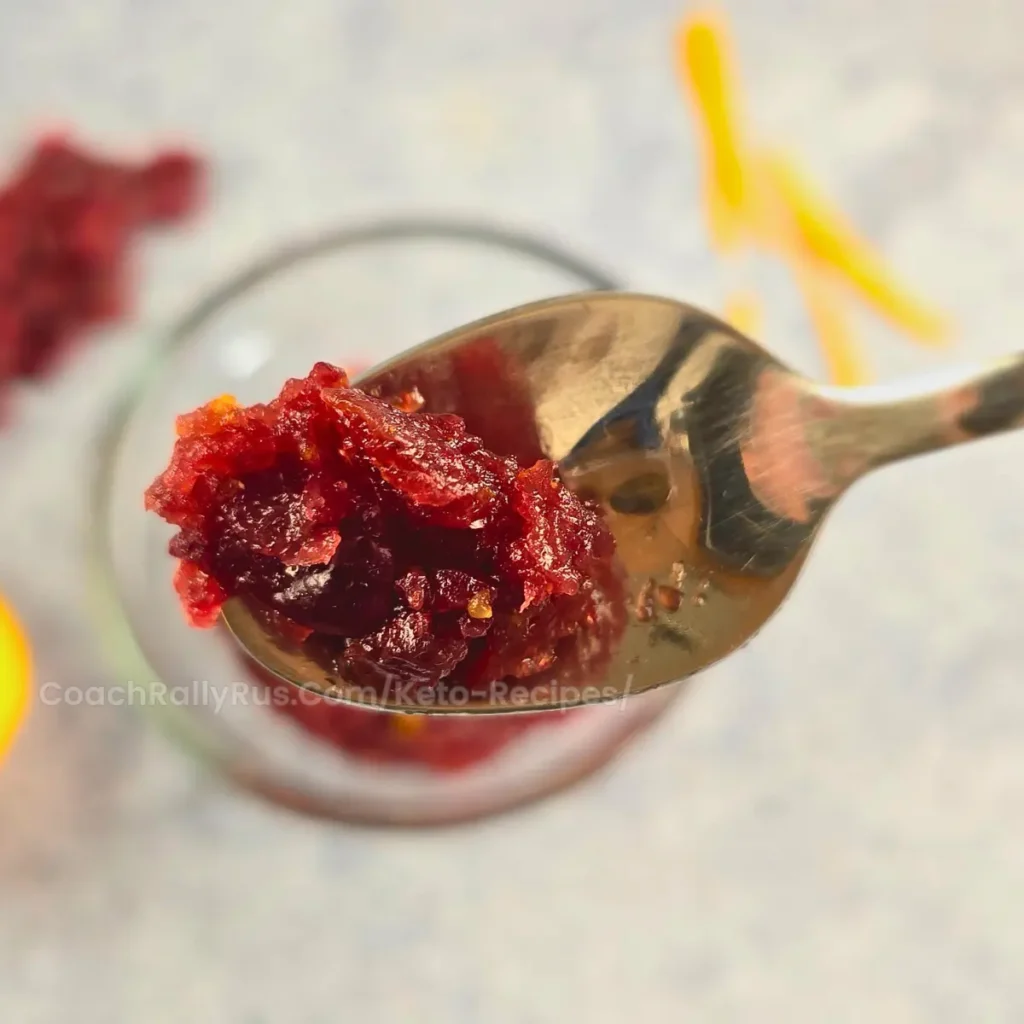 A spoonful of Spiced Keto Cranberry-Orange Relish, highlighting its rich, chunky texture and vibrant cranberry color.