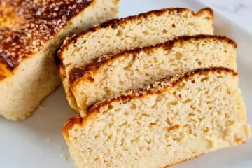 A freshly baked loaf of keto-friendly Cottage Cheese Bread with Almond Flour, showcasing a golden-brown crust and a soft, airy interior, served on a white plate.