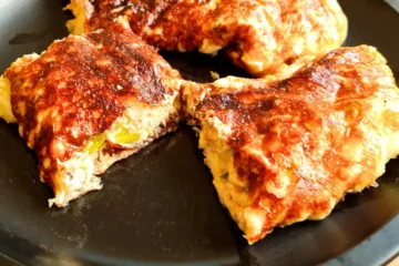 Golden, crispy keto tuna wraps made with a 1-ingredient mozzarella cheese wrap and a creamy tuna filling, served on a black plate.