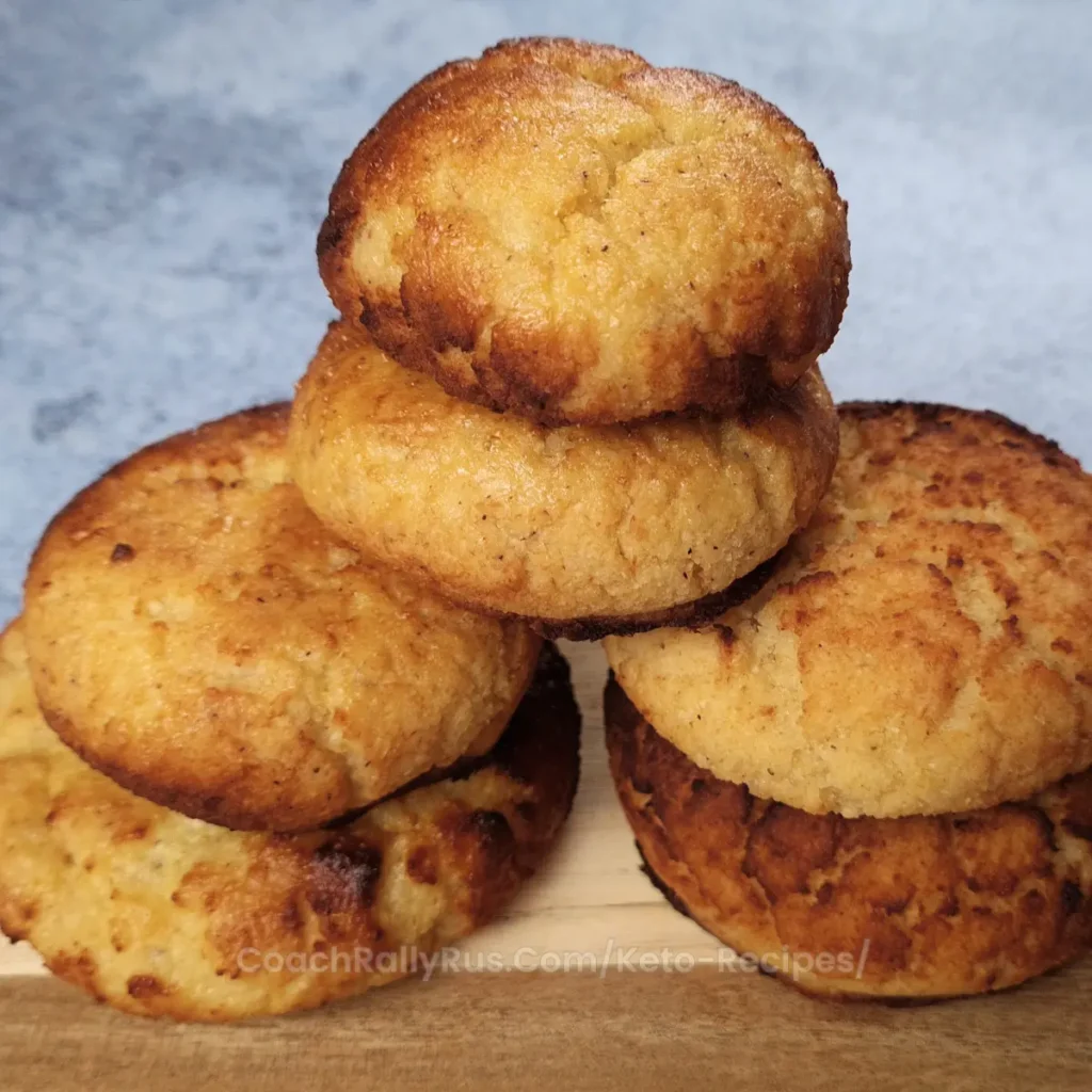Golden brown keto brioche buns stacked on a wooden board.