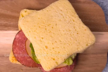 Keto cottage cheese mug bread sandwich with cheese and salami on a wooden board.