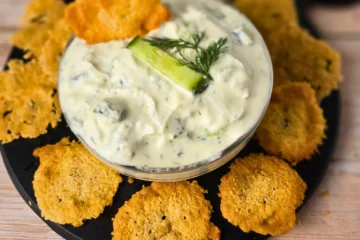 Crunchy baked parmesan chips next to a bowl of keto cucumber cottage cheese dip.