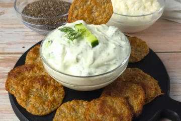 Keto Chia Seeds Cottage Cheese Chips on a black serving board with a bowl of cottage cheese dip and chia seeds.