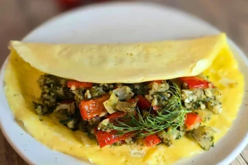 Mediterranean keto omelette with cauliflower rice, peppers, onions, and fresh dill on a white plate.