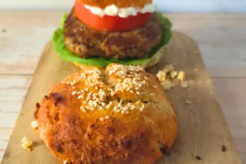 Keto burger served with egg free cottage cheese keto bun and an extra bun on a board.