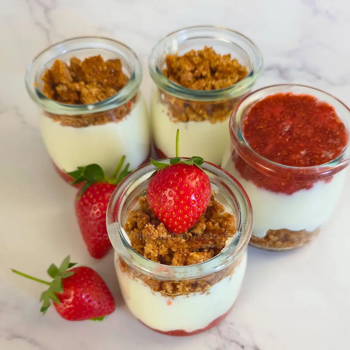 Multiple keto strawberry cottage cheese parfait jars topped with crumble and strawberries