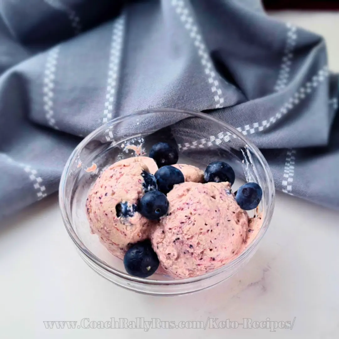 Keto blueberry ice cream scoops with fresh blueberries in glass bowl
