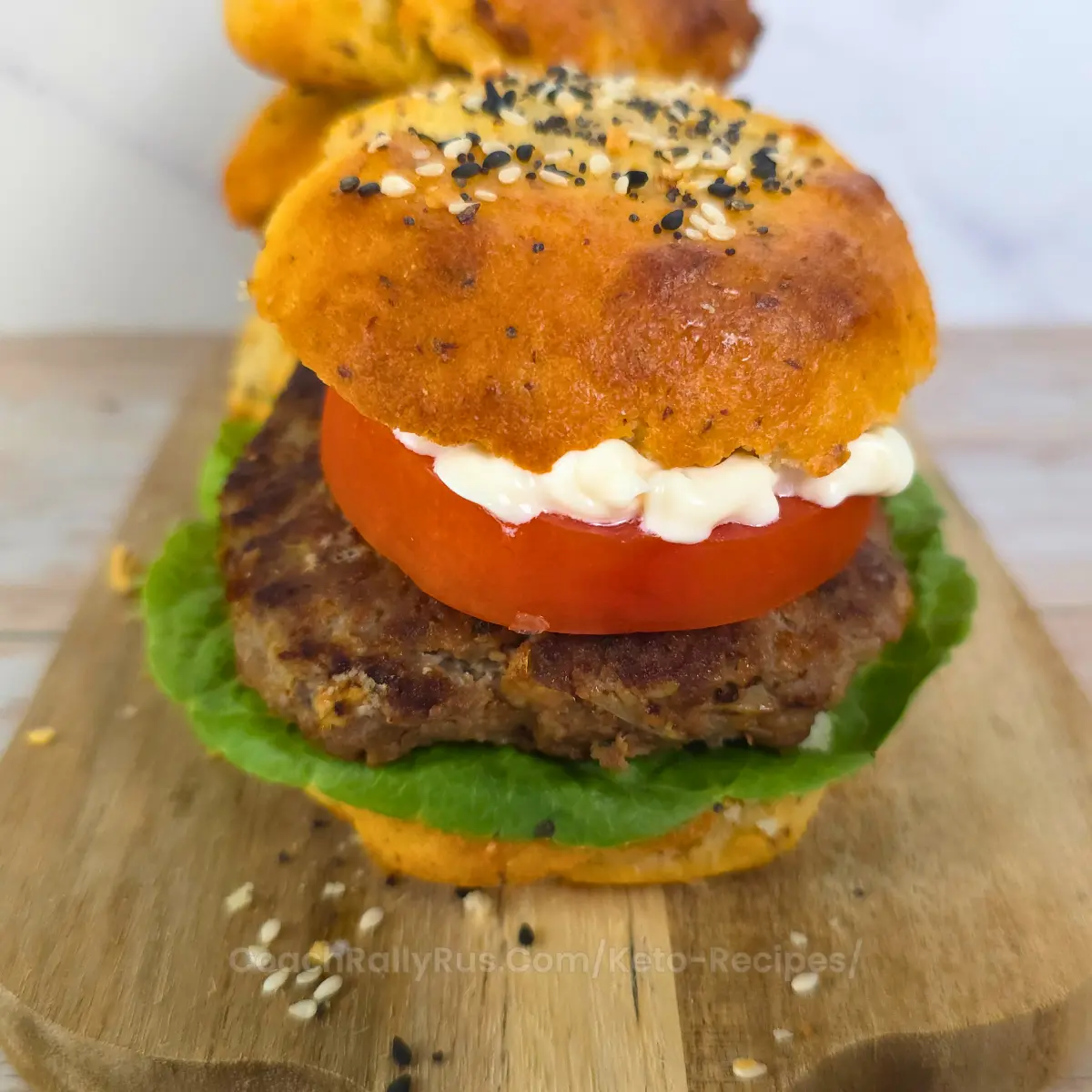 Assembled keto Mediterranean burger on a bun with tomato, mayo, and lettuce