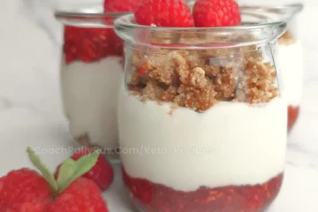 Keto raspberry parfait in glass jar topped with fresh raspberries and crumble