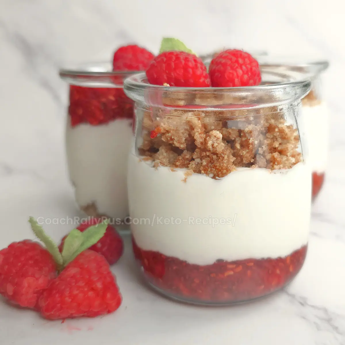 Keto raspberry parfait in glass jar topped with fresh raspberries and crumble