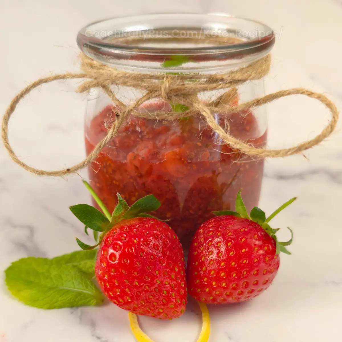 Glass jar filled with keto strawberry chia seed jam and fresh strawberries in front
