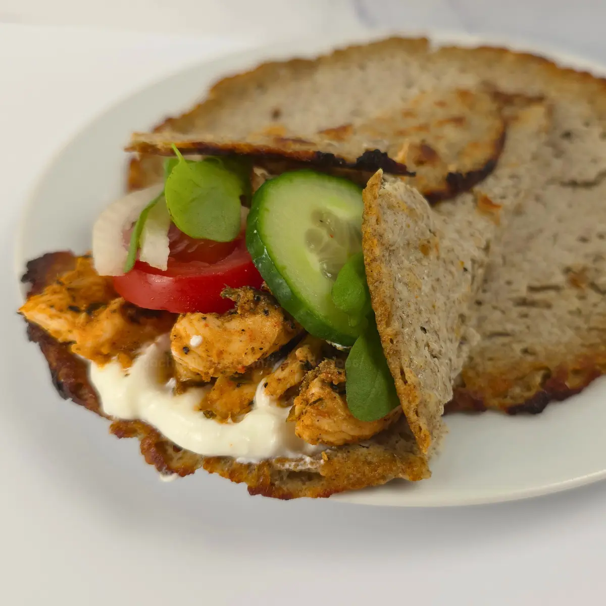 keto cottage cheese wrap filled with chicken, cucumber, tomato, and sauce