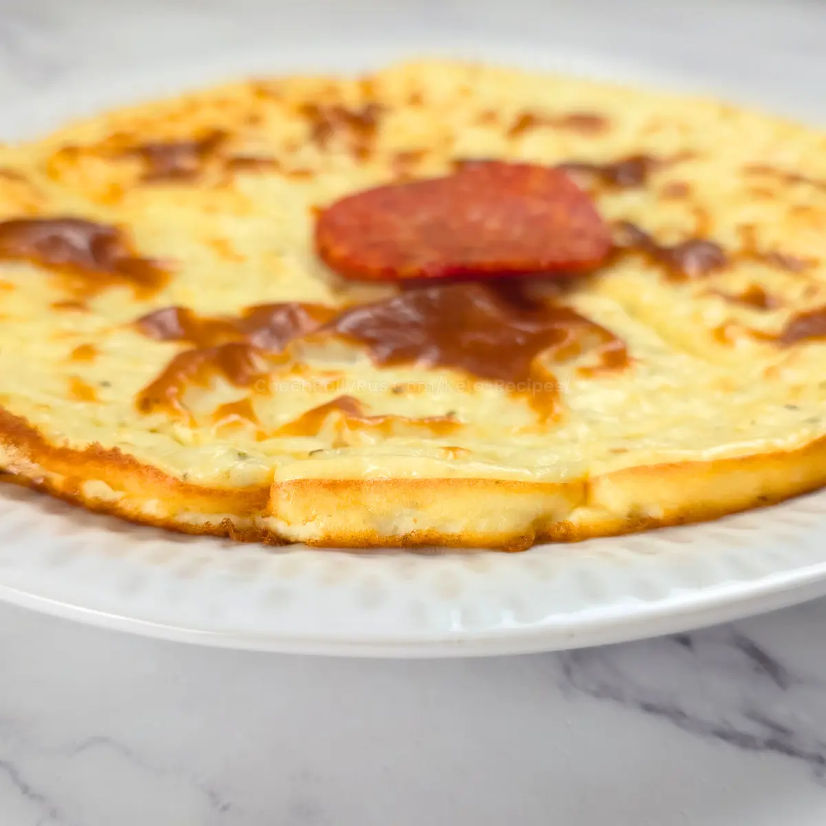 Baked cottage cheese pizza crust with golden edges and a pepperoni slice