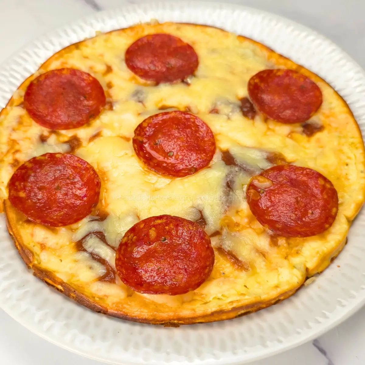 Whole keto pizza crust with melted cheese and pepperoni