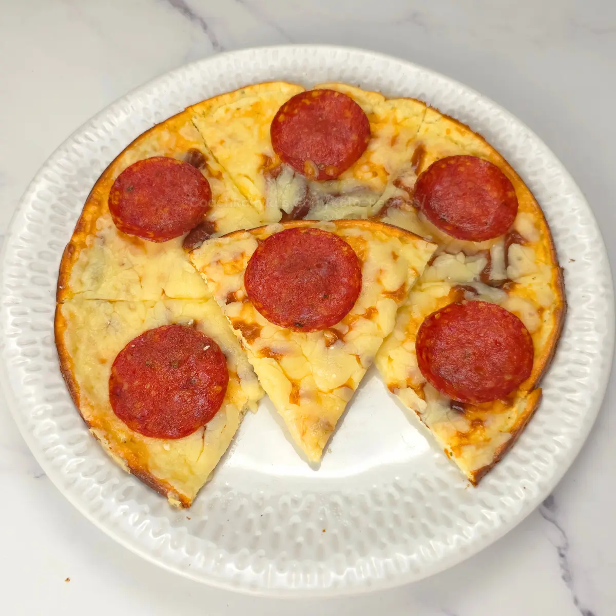 Sliced keto pizza with pepperoni made on cottage cheese coconut flour crust