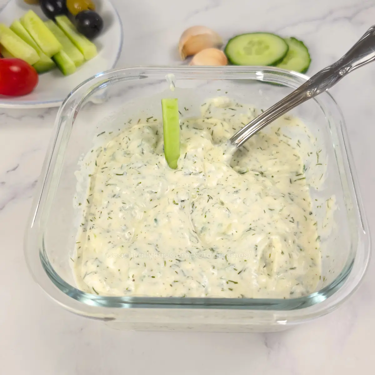 Cottage cheese tzatziki in a glass dish with cucumber stick and spoon