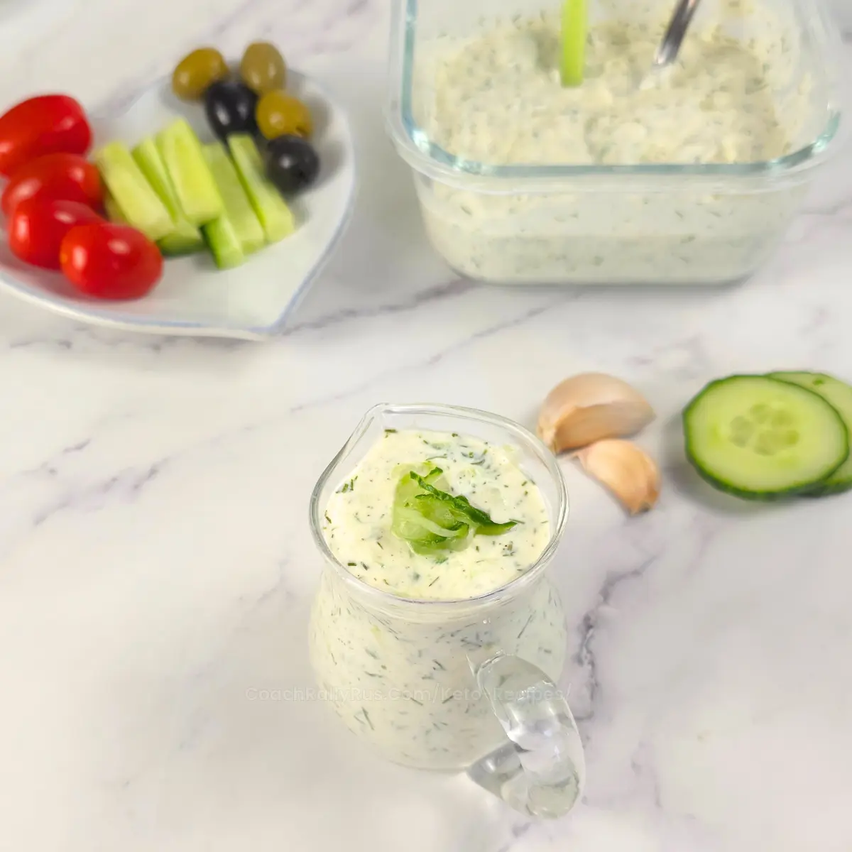 Cottage cheese tzatziki served in a glass pitcher with cucumbers and garlic