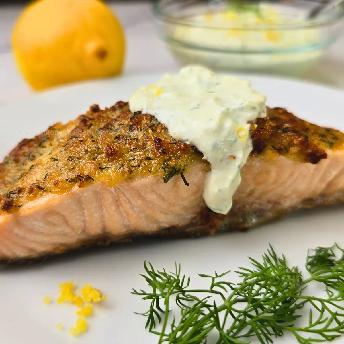 Close-up of salmon fillet topped with creamy lemon dill sauce