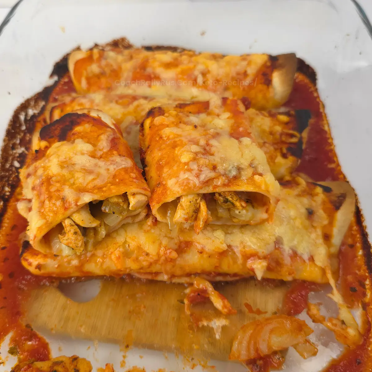 Chicken enchiladas with gyro filling and cheese in glass casserole