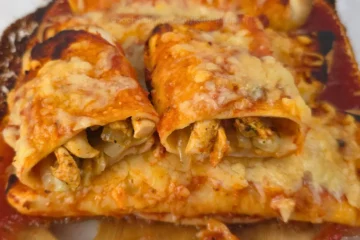 Chicken gyros enchiladas baked with cheese in a glass casserole dish