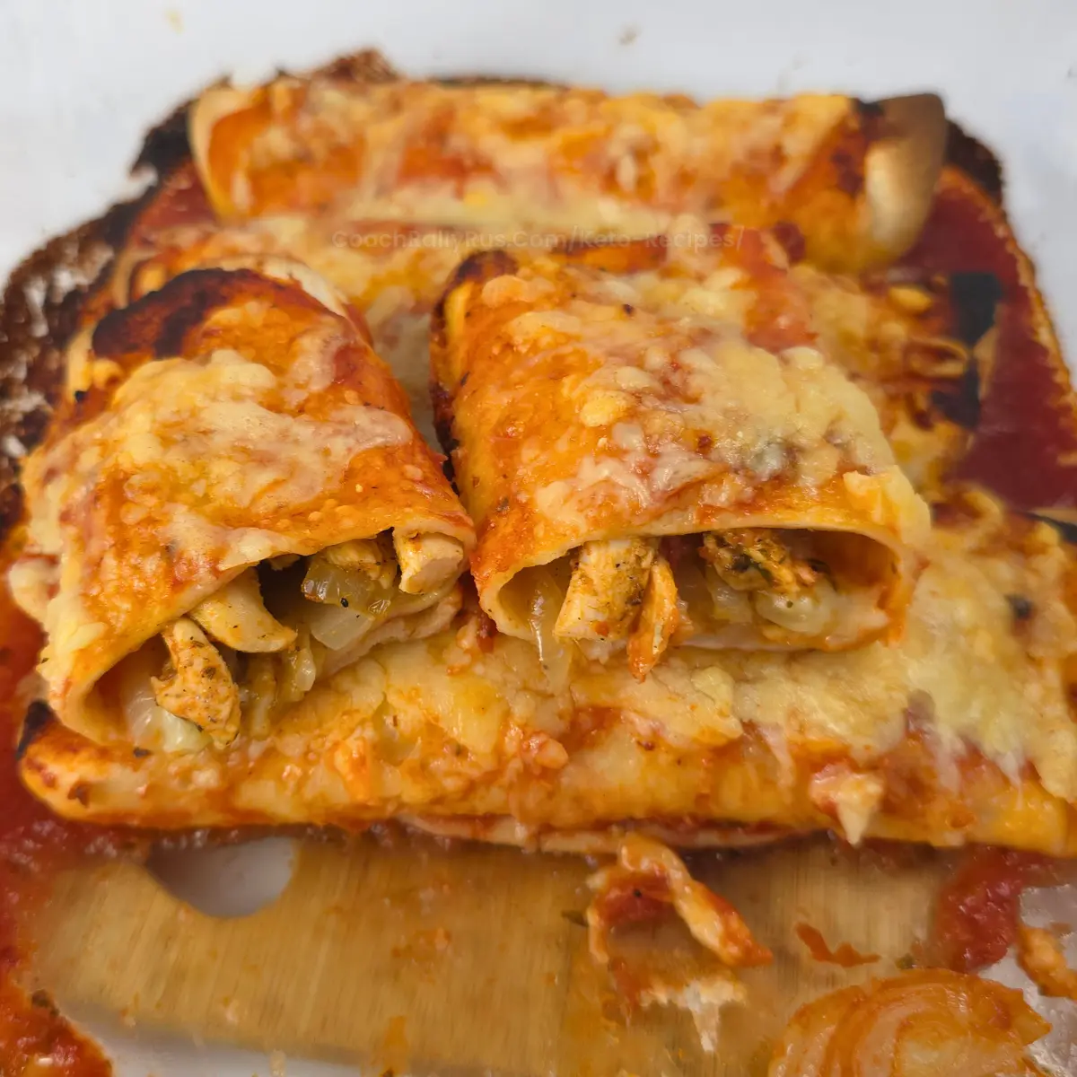 Chicken gyros enchiladas baked with cheese in a glass casserole dish