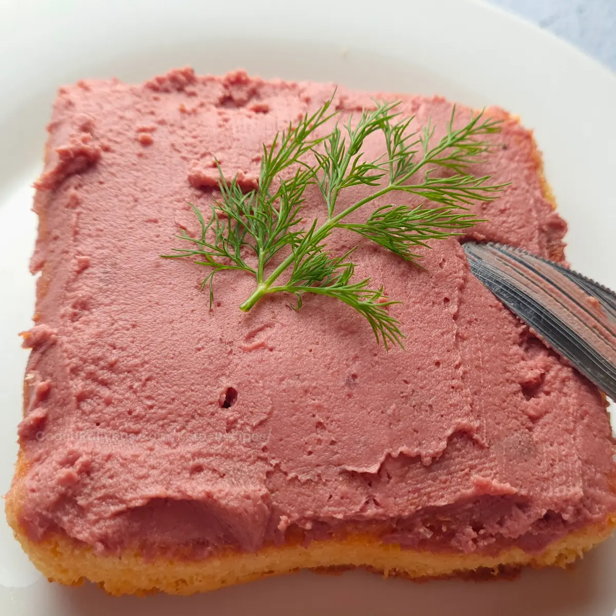 Close-up of creamy chicken liver pate being spread with knife