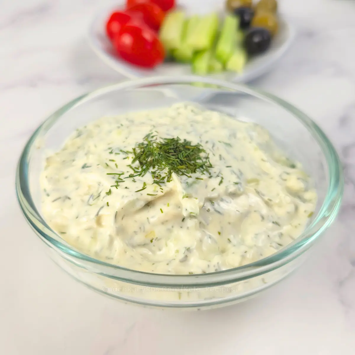 Creamy keto tzatziki sauce with sour cream in a glass bowl with garnish
