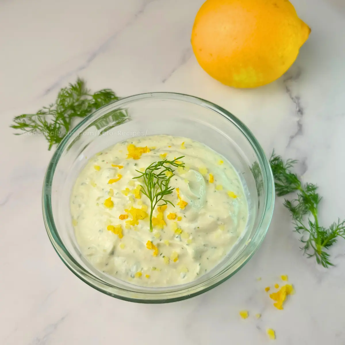 Creamy high-protein lemon dill cottage cheese sauce in a glass bowl with lemon zest and fresh dill