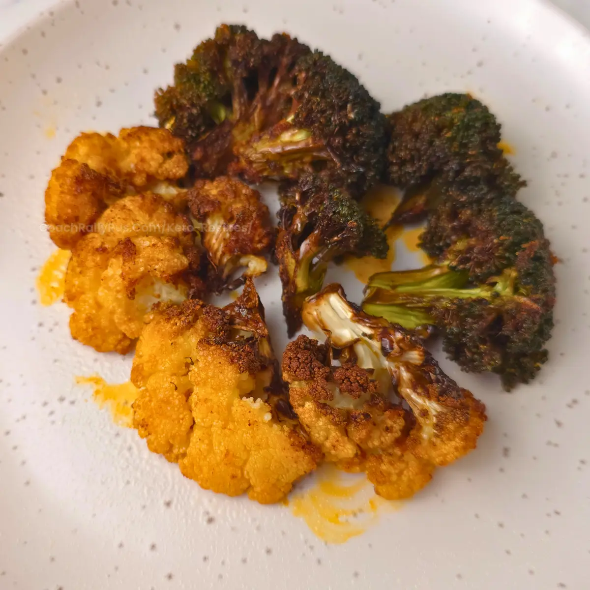 Mixed roasted broccoli and cauliflower on white speckled plate