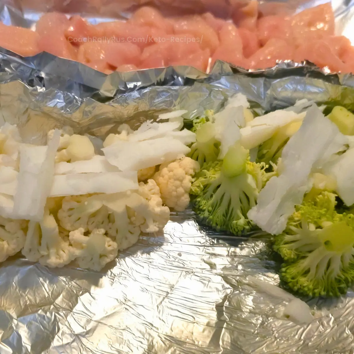 raw cauliflower and broccoli with beef fat slices on foil sheet