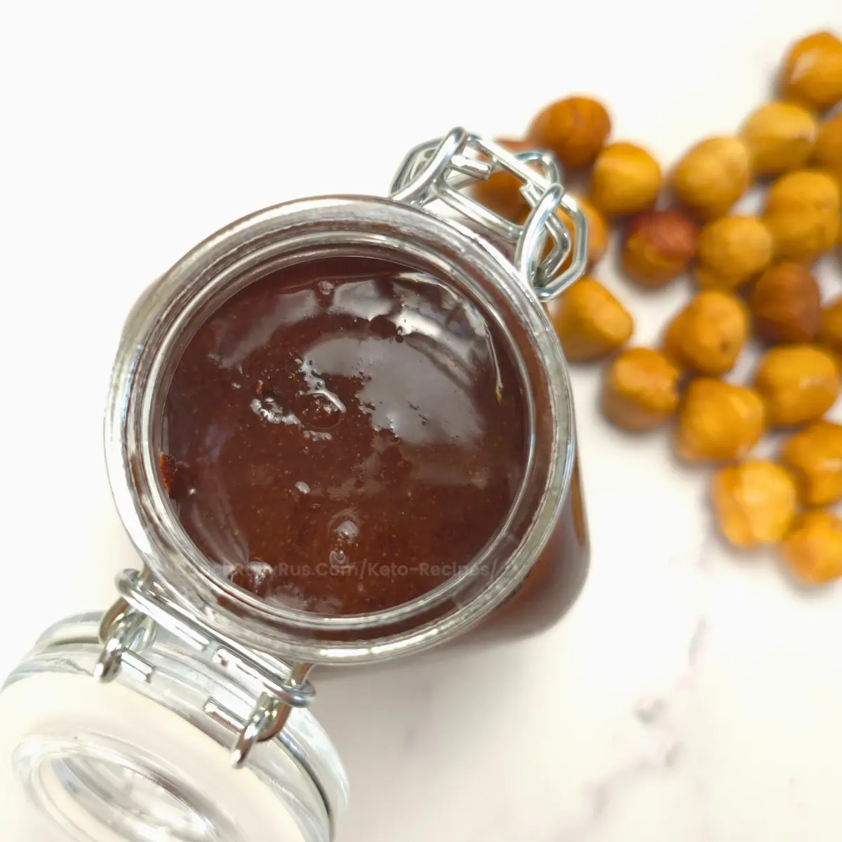Top view of keto Nutella in jar with hazelnuts